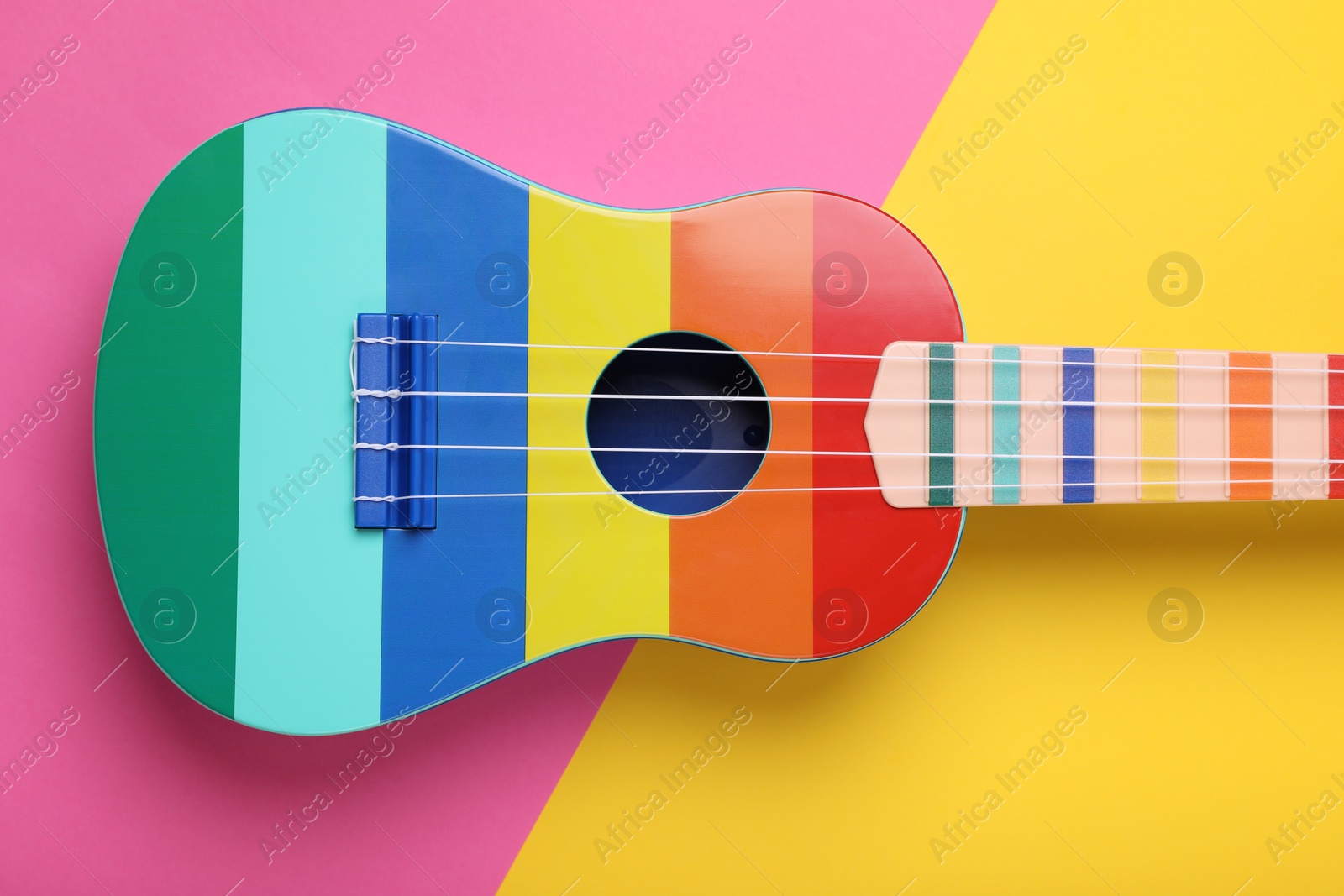 Photo of Bright ukulele on color background, top view. String musical instrument