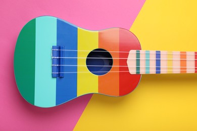 Photo of Bright ukulele on color background, top view. String musical instrument