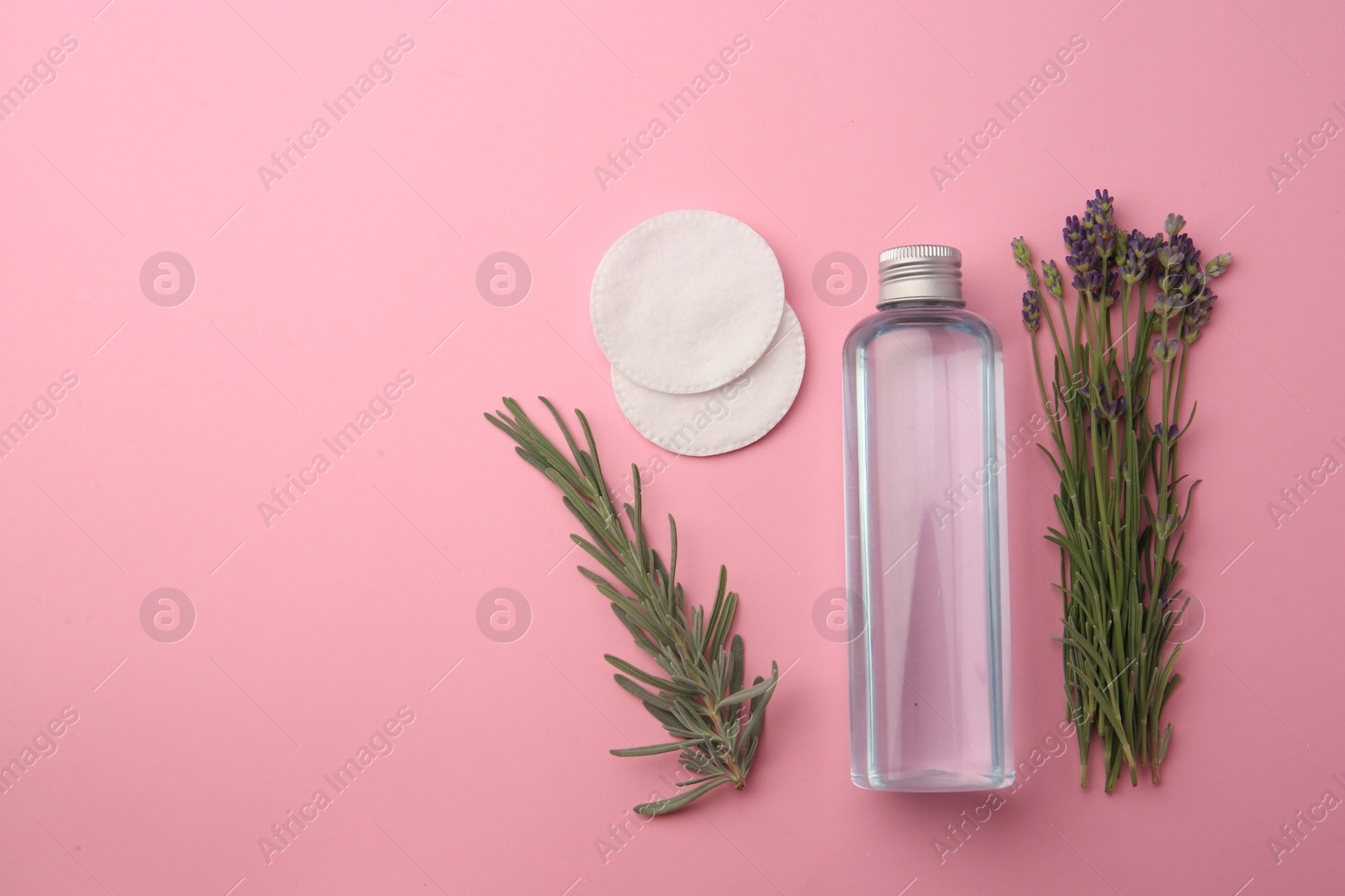 Photo of Flat lay composition with bottle of makeup remover and cotton pads on pink background. Space for text