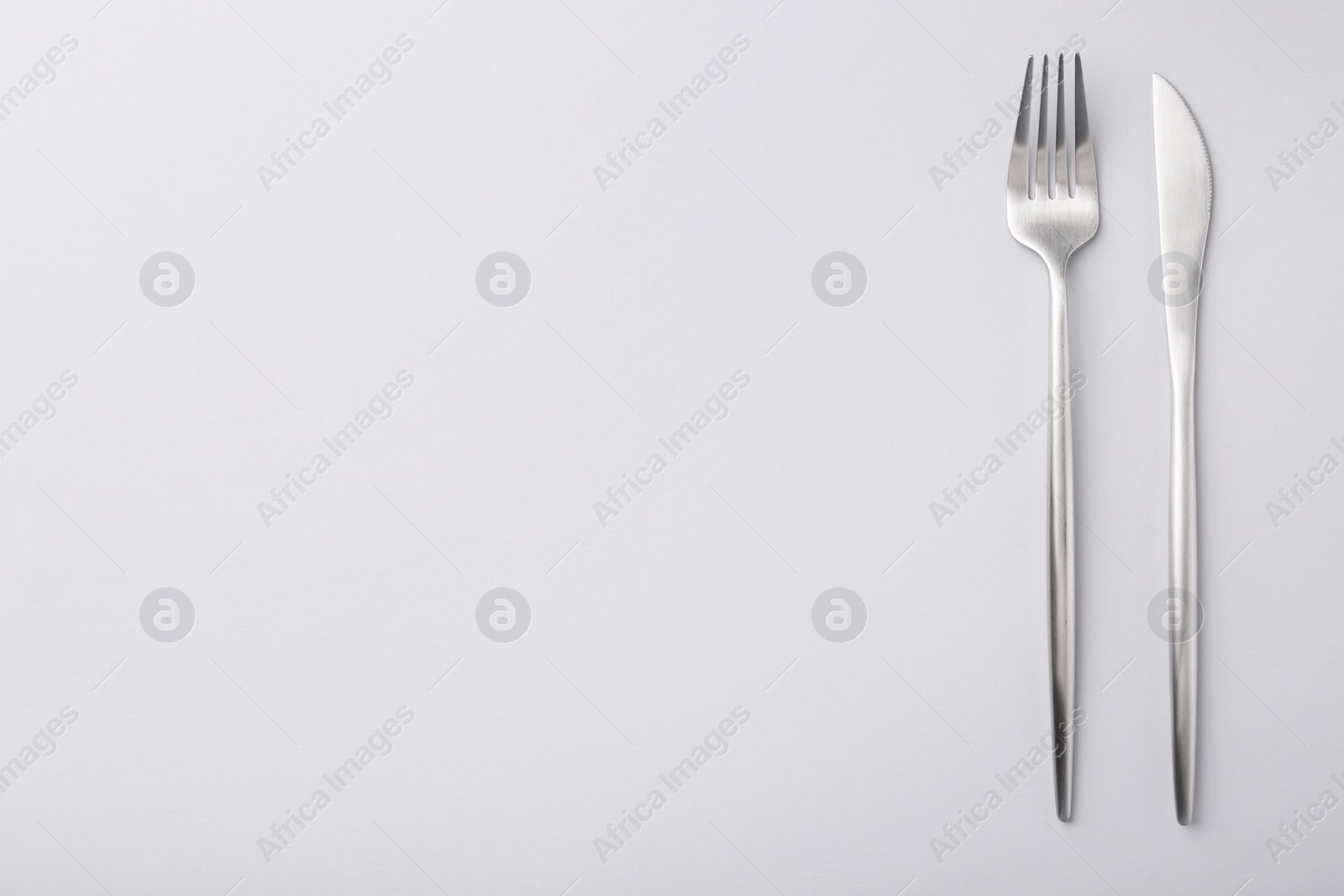 Photo of Stylish cutlery on grey table, top view. Space for text