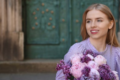 Beautiful woman with bouquet of spring flowers outdoors, space for text