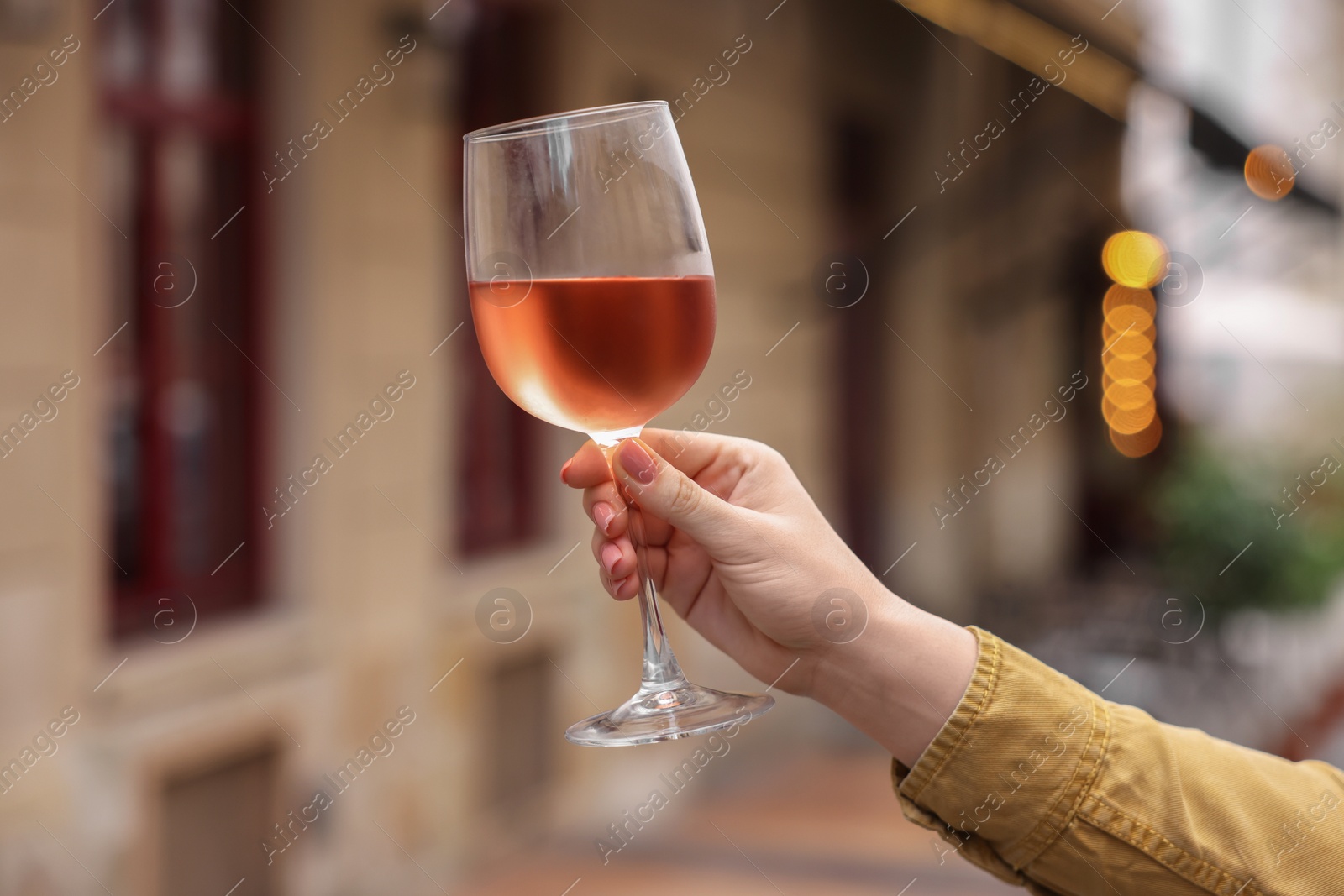 Photo of Woman holding glass of rose wine outdoors, closeup