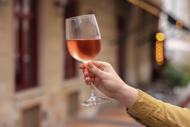 Woman holding glass of rose wine outdoors, closeup