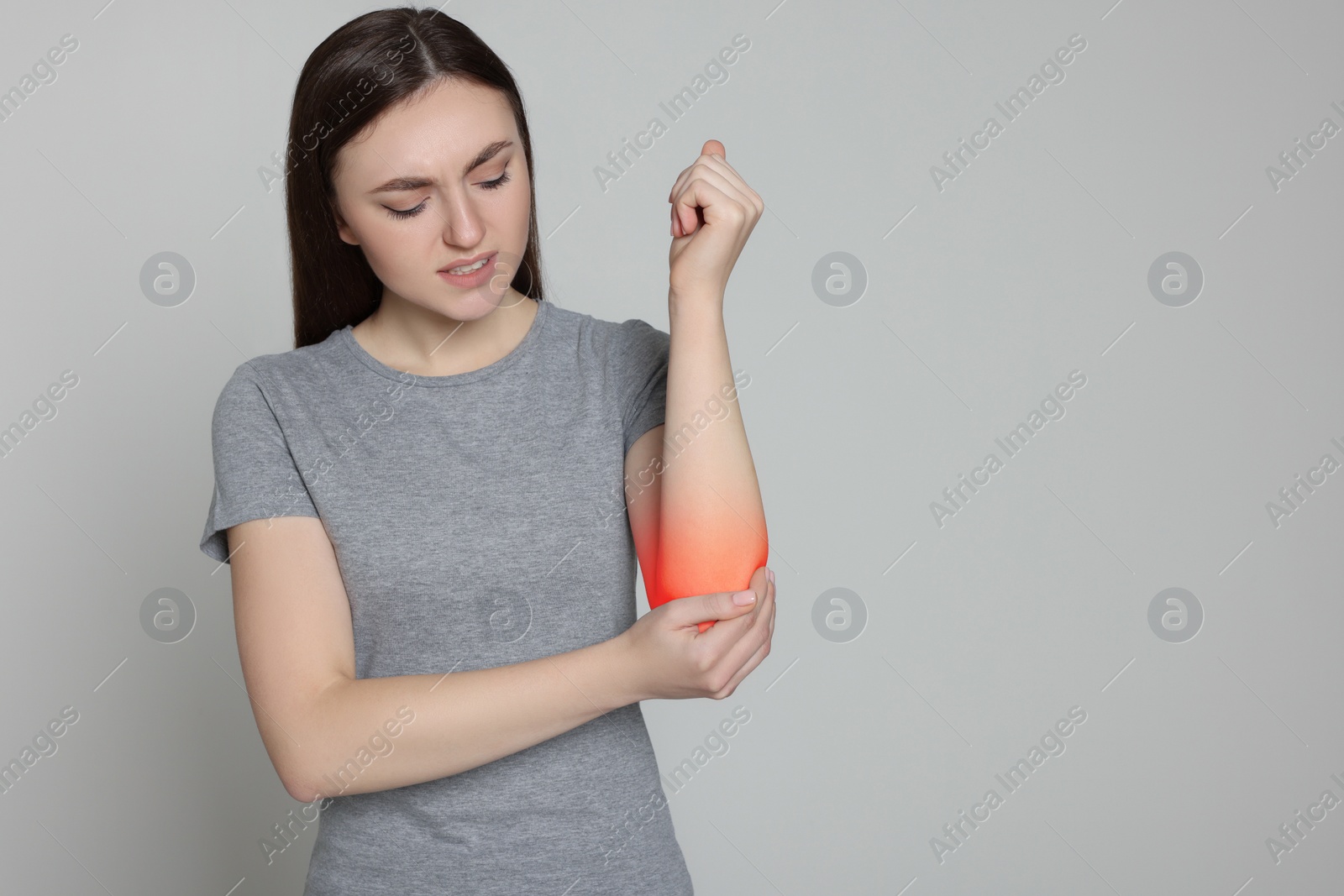 Image of Woman suffering from pain in elbow on grey background. Space for text