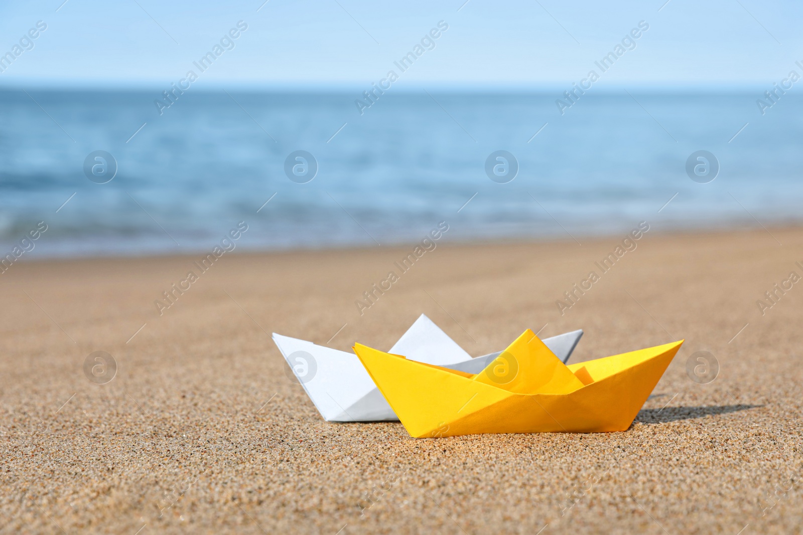 Photo of Color paper boats near sea on sandy beach