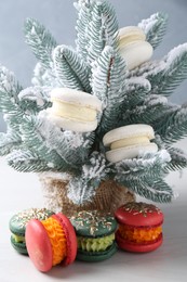 Different decorated Christmas macarons and fir branches with snow on white table