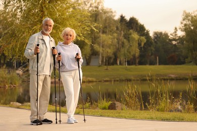 Photo of Senior man and woman with Nordic walking outdoors, space for text