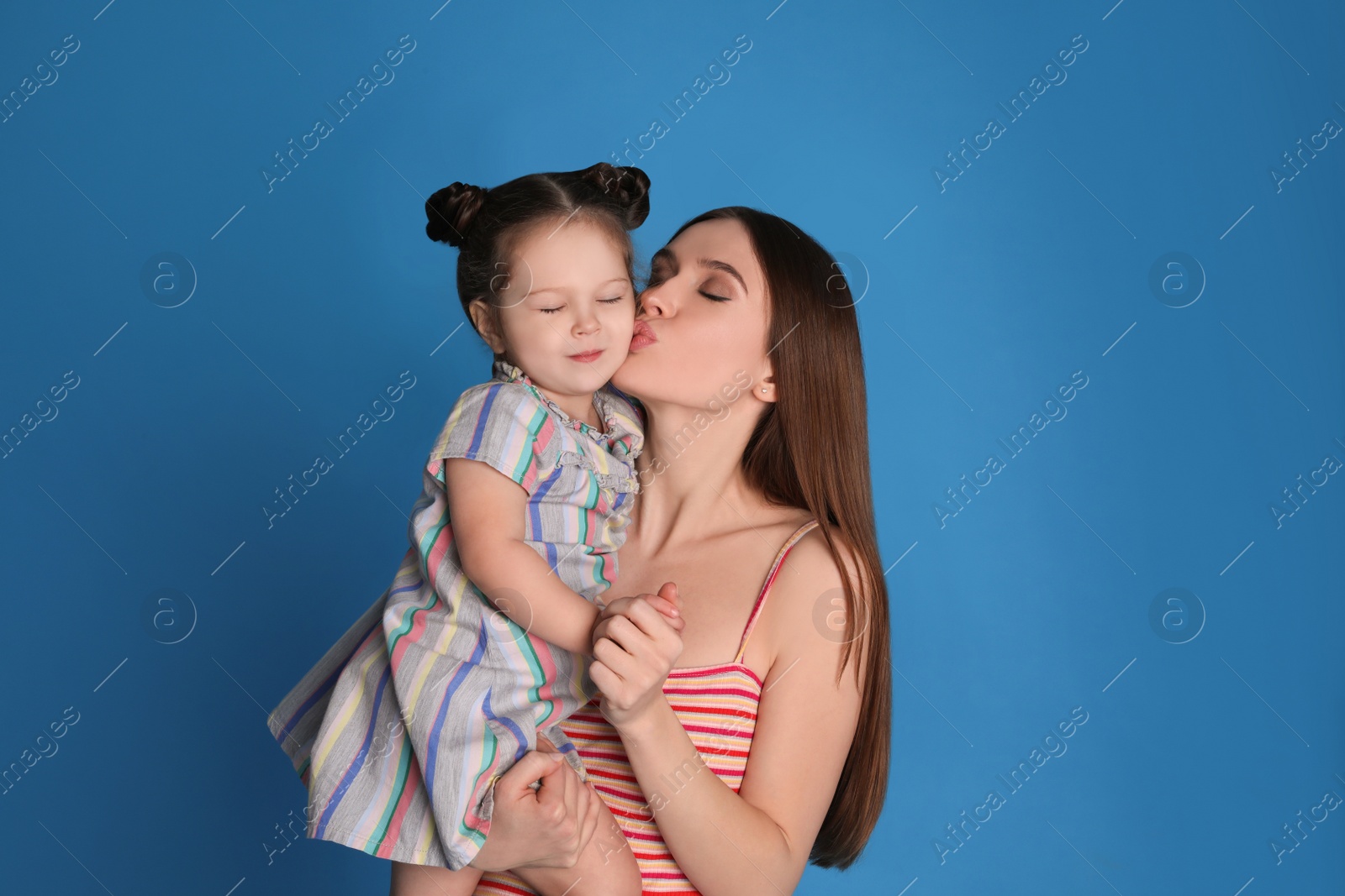 Photo of Young mother and little daughter on blue background