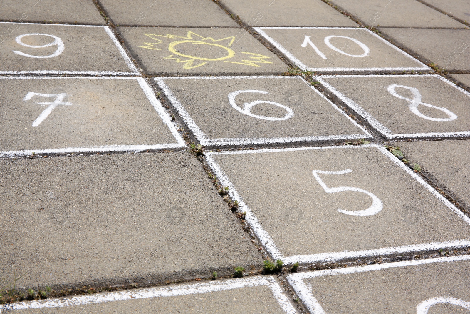 Photo of Hopscotch drawn with white chalk on street tiles outdoors, closeup