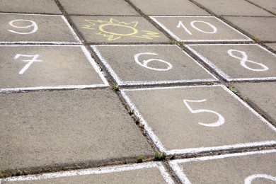 Hopscotch drawn with white chalk on street tiles outdoors, closeup