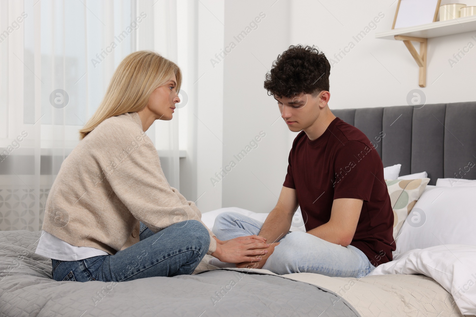 Photo of Mother consoling her upset son in bedroom. Teenager problems