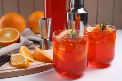 Photo of Aperol spritz cocktail, rosemary and orange slices on white wooden table