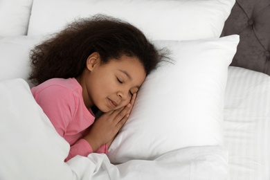 Photo of Cute little African-American girl sleeping in bed