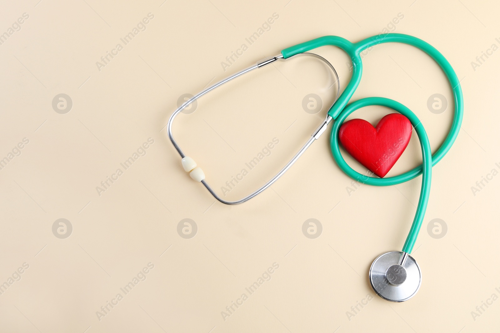 Photo of Stethoscope and red heart on beige background, top view. Space for text