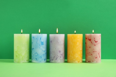 Photo of Alight scented wax candles on color background