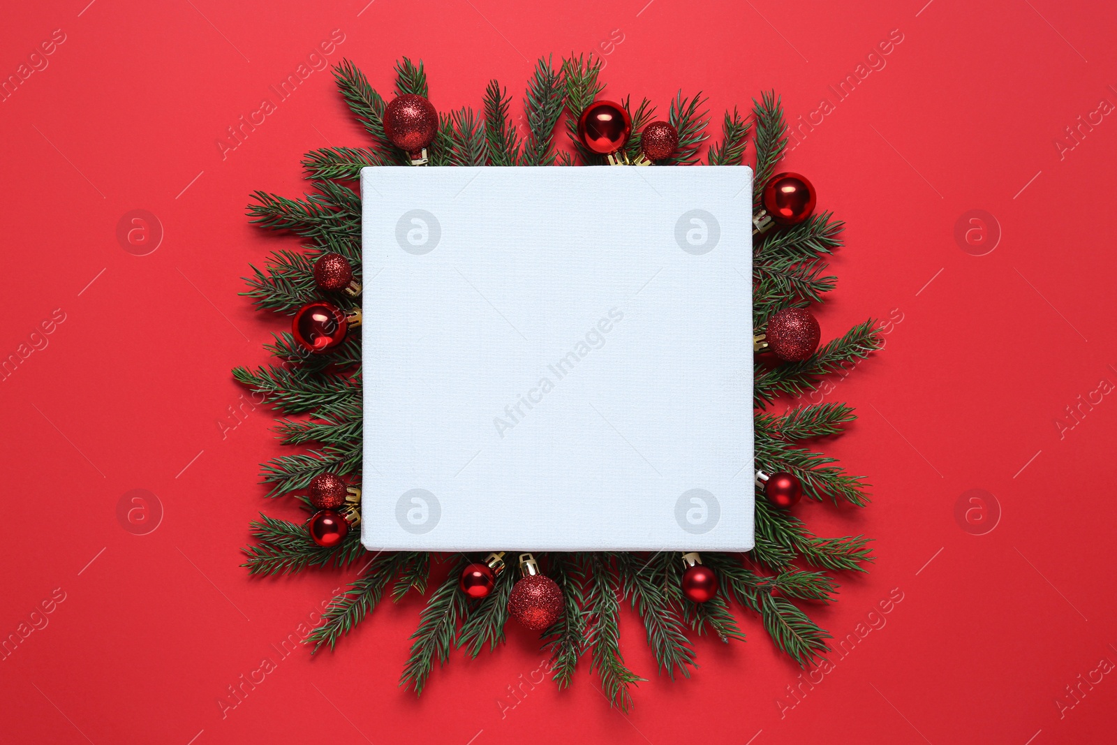 Photo of Blank canvas and Christmas decor on red background, flat lay. Space for design