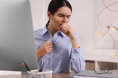 Woman with tissue coughing at table in office. Cold symptoms