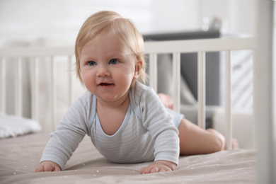 Photo of Adorable little baby lying in comfortable crib