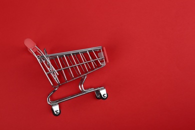 Empty shopping trolley on color background, top view. Space for text