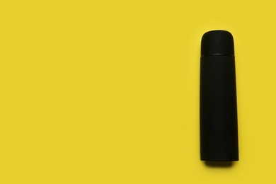 Photo of Black thermos on yellow background, top view. Space for text