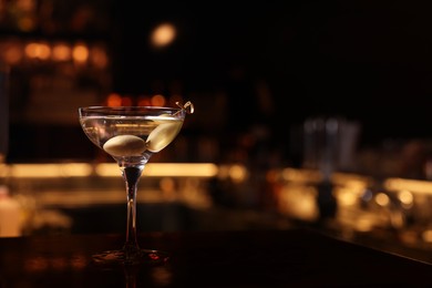 Photo of Martini glass with fresh cocktail and olives on bar counter, space for text