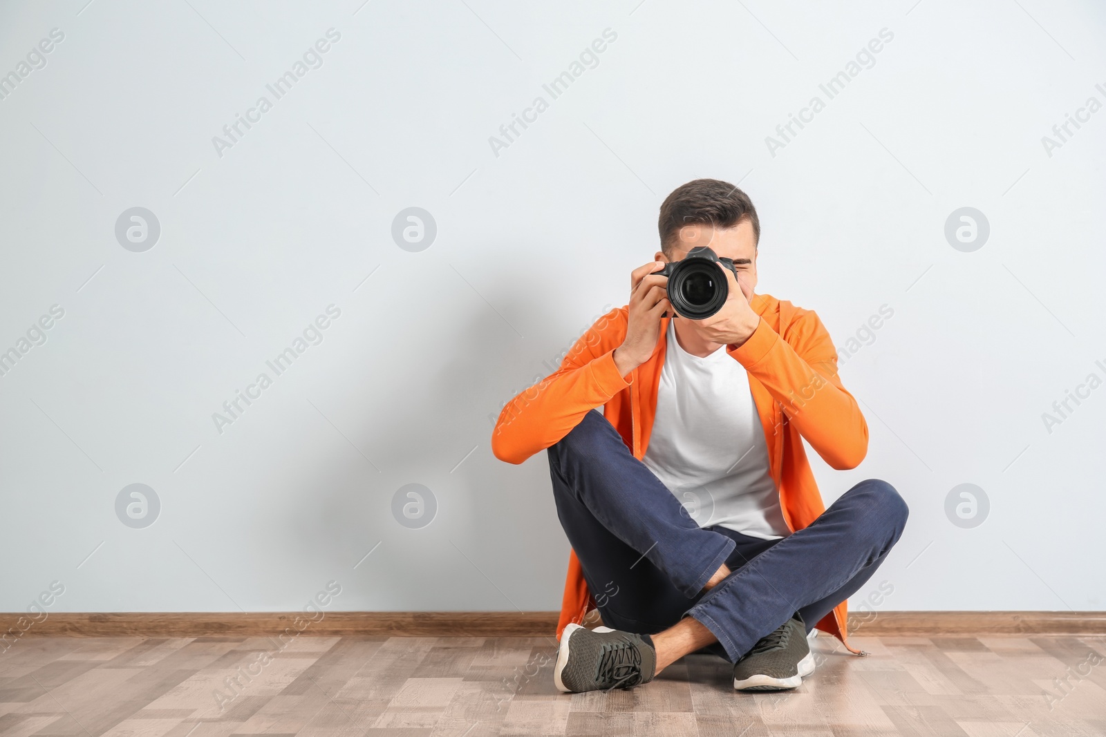 Photo of Male photographer with camera near light wall