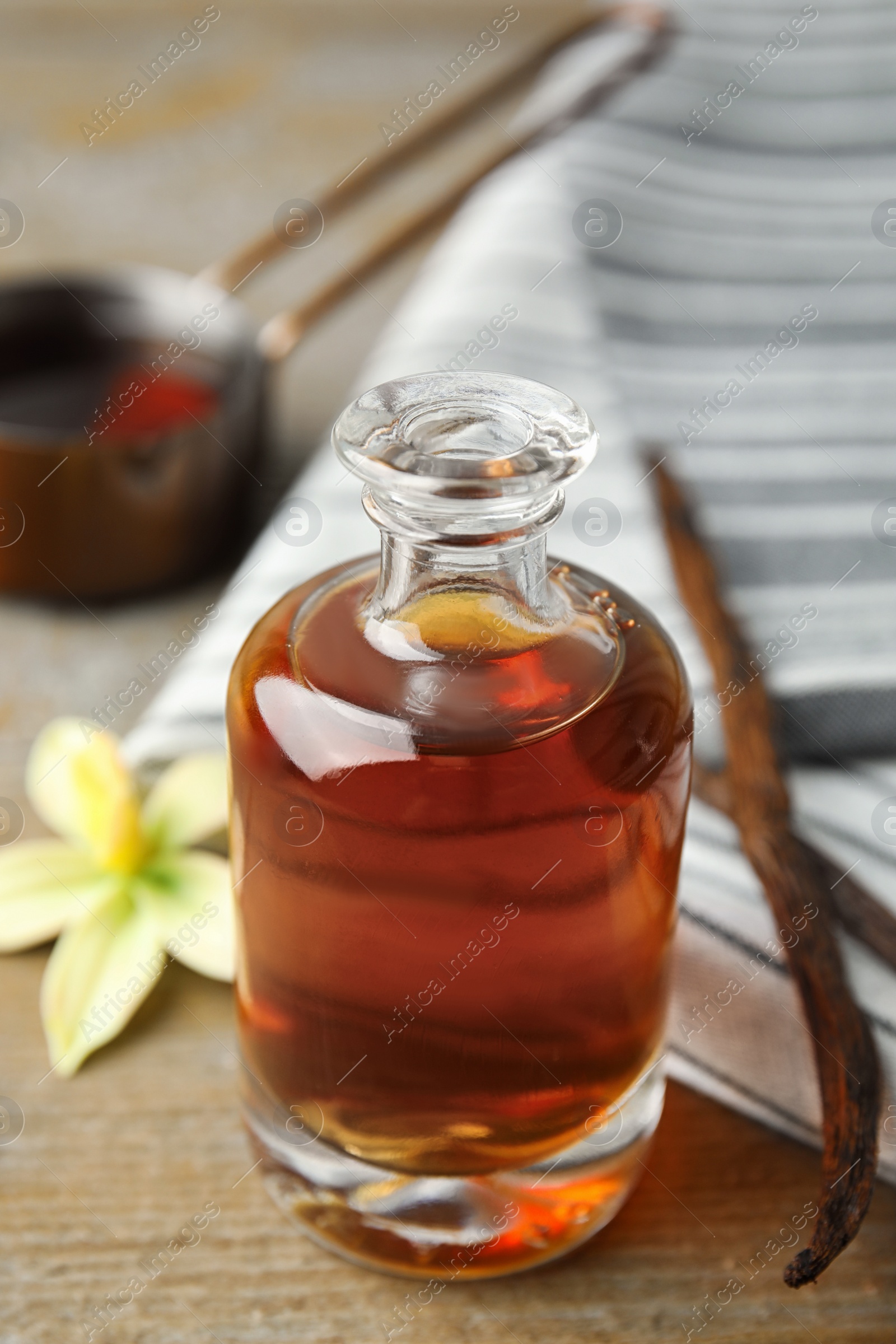 Photo of Aromatic homemade vanilla extract on wooden table, closeup