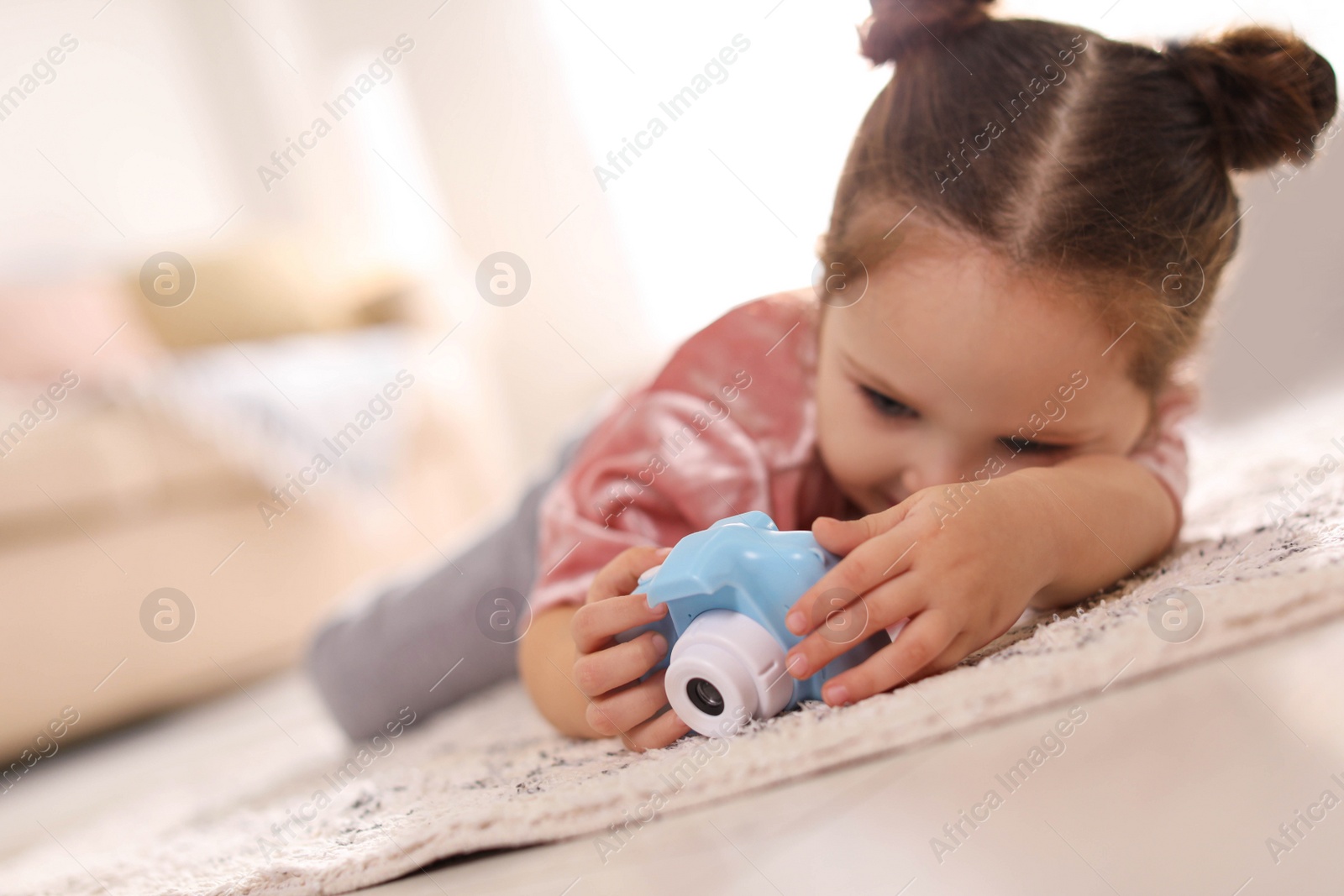 Photo of Little photographer with toy camera on floor at home. Space for text