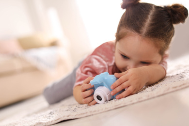 Little photographer with toy camera on floor at home. Space for text