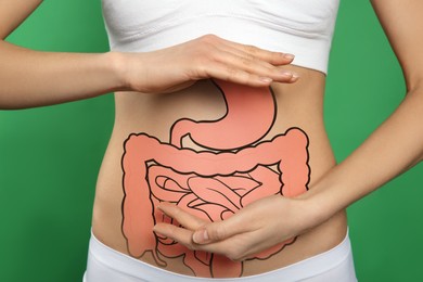 Woman with image of healthy digestive system on green background, closeup