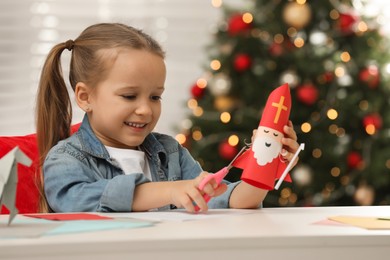 Cute little girl making paper Saint Nicholas toy at home