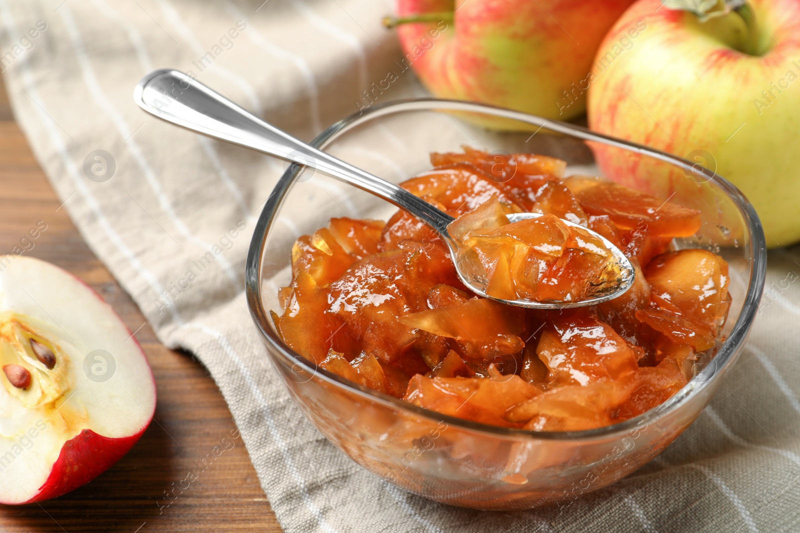 Photo of Tasty apple jam in glass bowl and fresh fruits on table, closeup