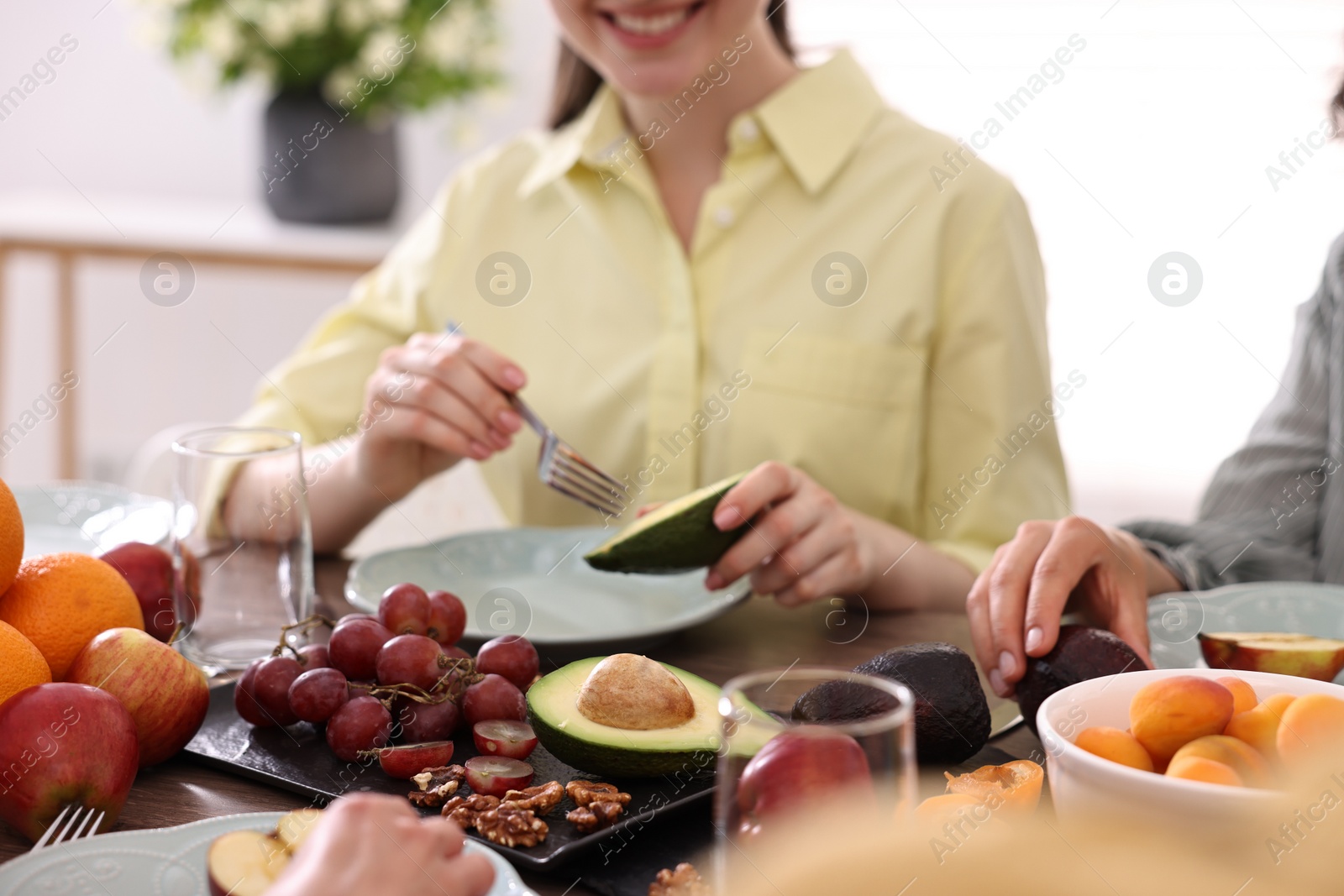 Photo of Friends eating vegetarian food at table indoors, closeup