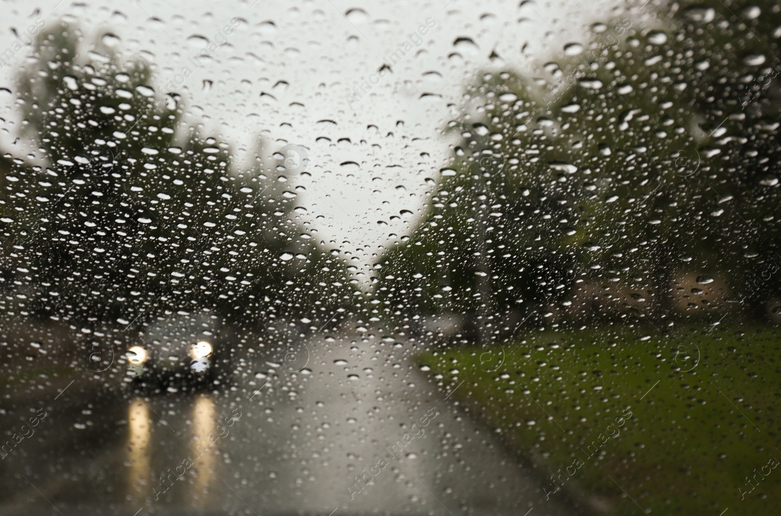 Photo of Blurred view of road through wet car window. Rainy weather