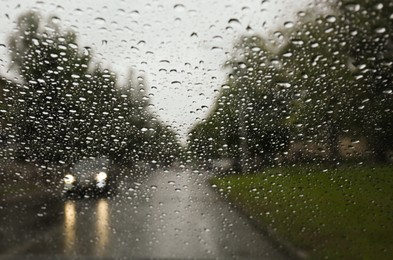 Blurred view of road through wet car window. Rainy weather