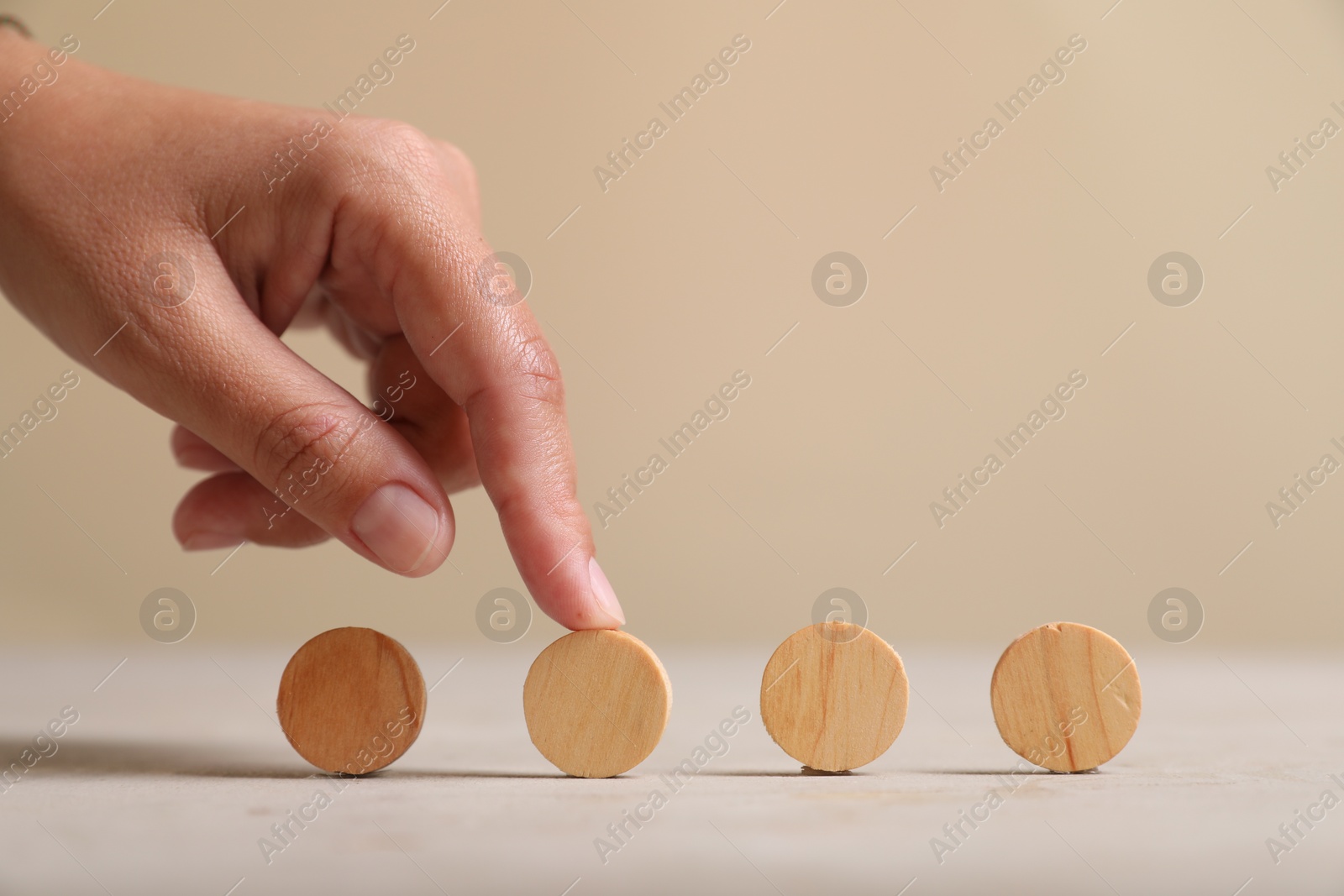 Photo of Choice concept. Woman choosing wooden circle among others at light table, closeup