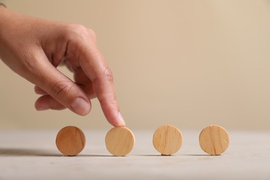 Photo of Choice concept. Woman choosing wooden circle among others at light table, closeup