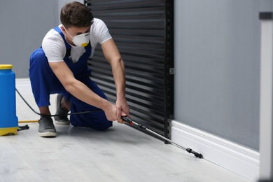 Pest control worker spraying pesticide in room