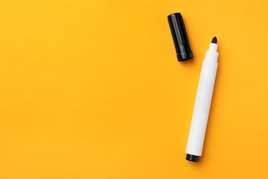 Photo of Black marker on orange background, flat lay. Space for text