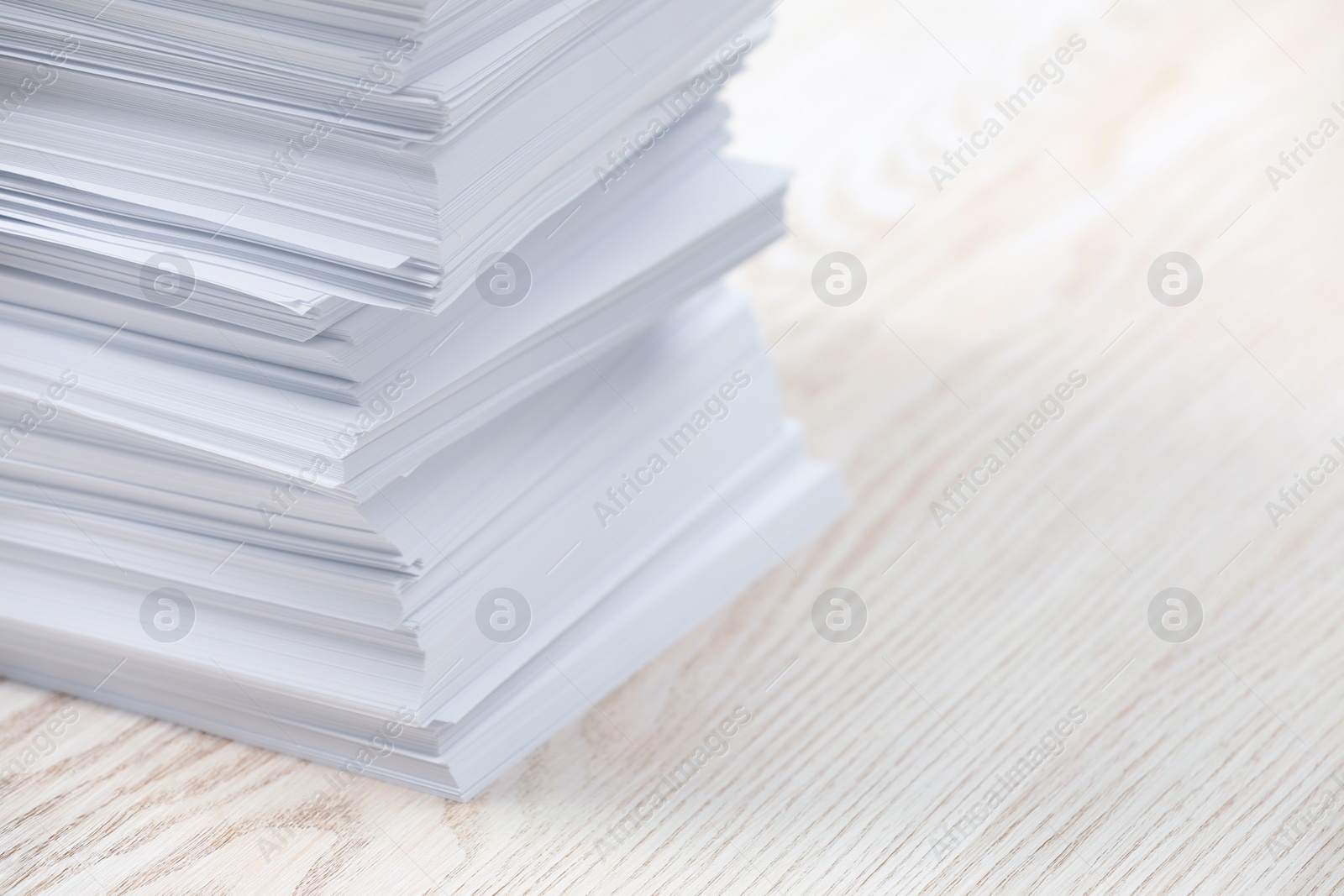 Photo of Stack of paper sheets on white wooden table, closeup. Space for text