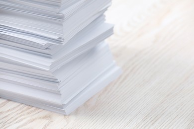 Photo of Stack of paper sheets on white wooden table, closeup. Space for text