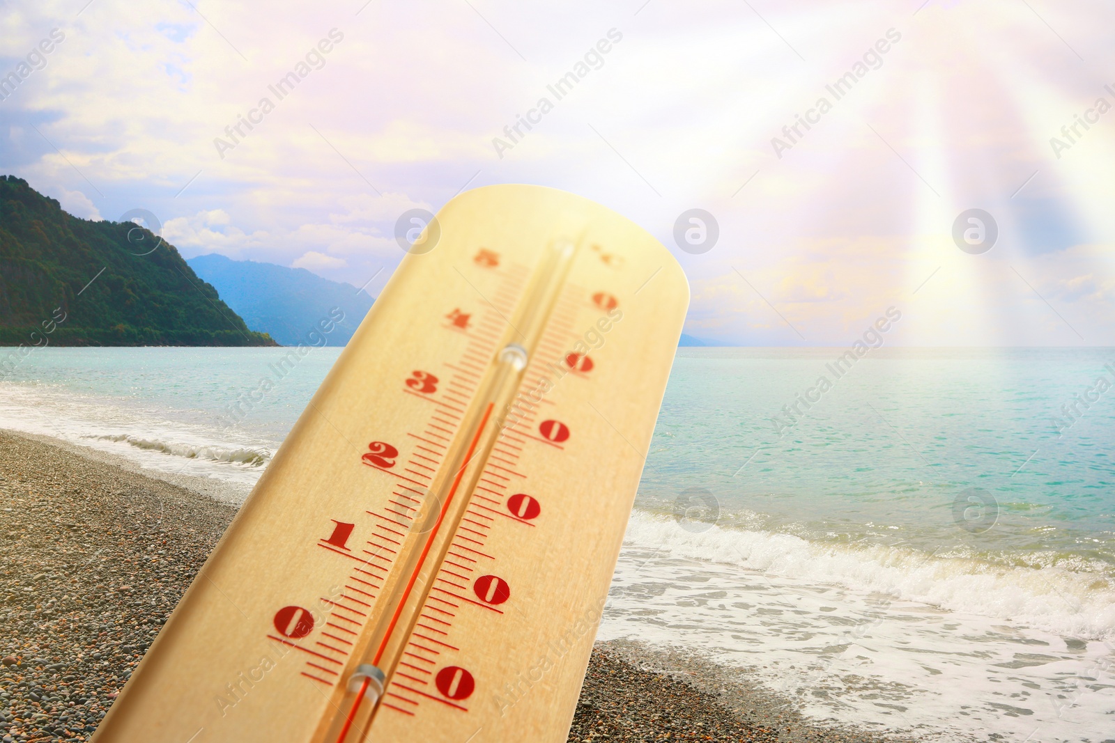 Image of Thermometer in sand on beach during sunny summer day