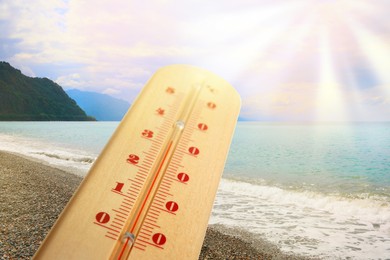 Image of Thermometer in sand on beach during sunny summer day