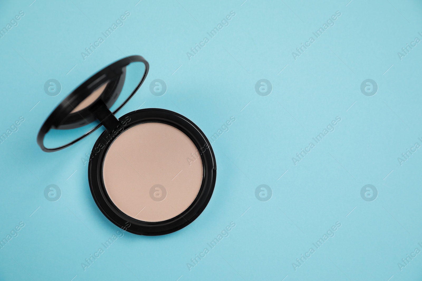 Photo of One face powder on light blue background, top view with space for text
