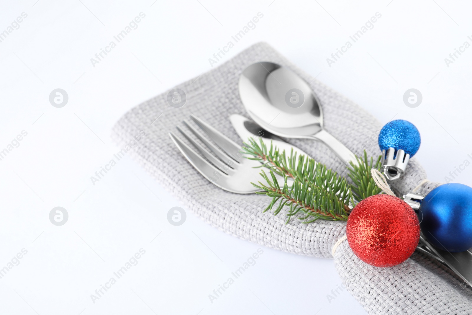 Photo of Cutlery, napkin and Christmas decor on white background, closeup. Festive table setting