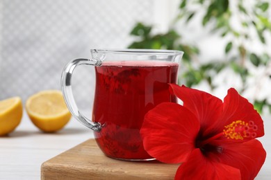 Delicious hibiscus tea and beautiful flower on white table, closeup