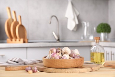 Bowl of fresh raw garlic on wooden table in kitchen