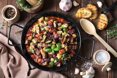 Photo of Delicious ratatouille in baking dish served on wooden table, flat lay