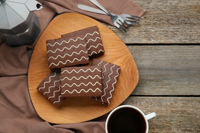 Tasty chocolate sponge cakes and hot drink on wooden table, flat lay. Space for text