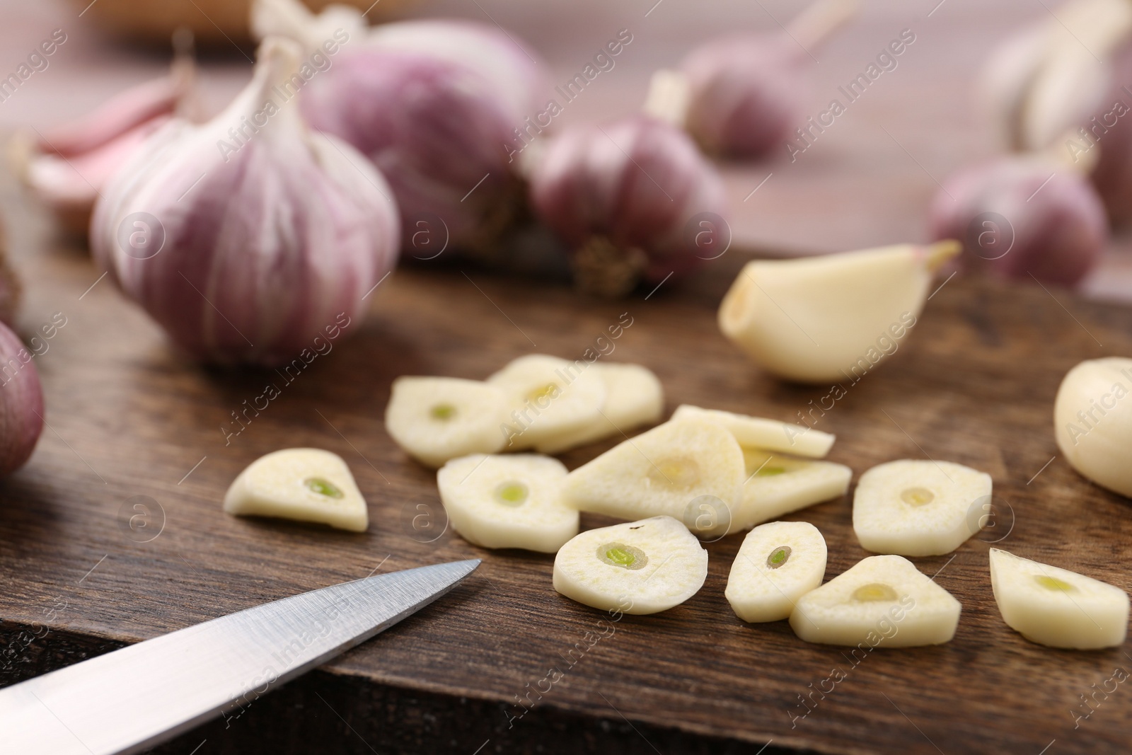 Photo of Pieces of fresh garlic and knife on table, selective focus